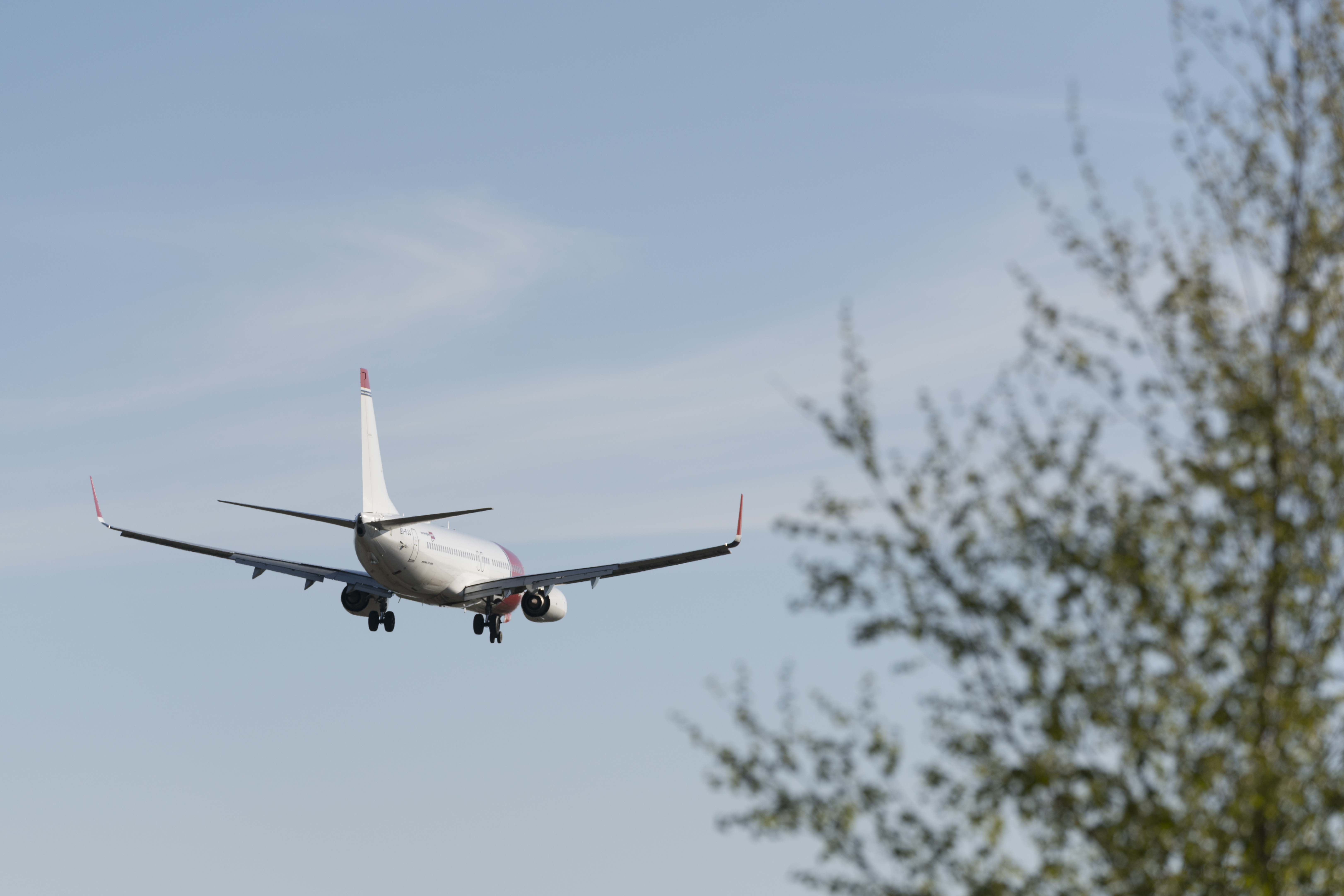 A commercial airplane flying low in the sky with its landing gear down